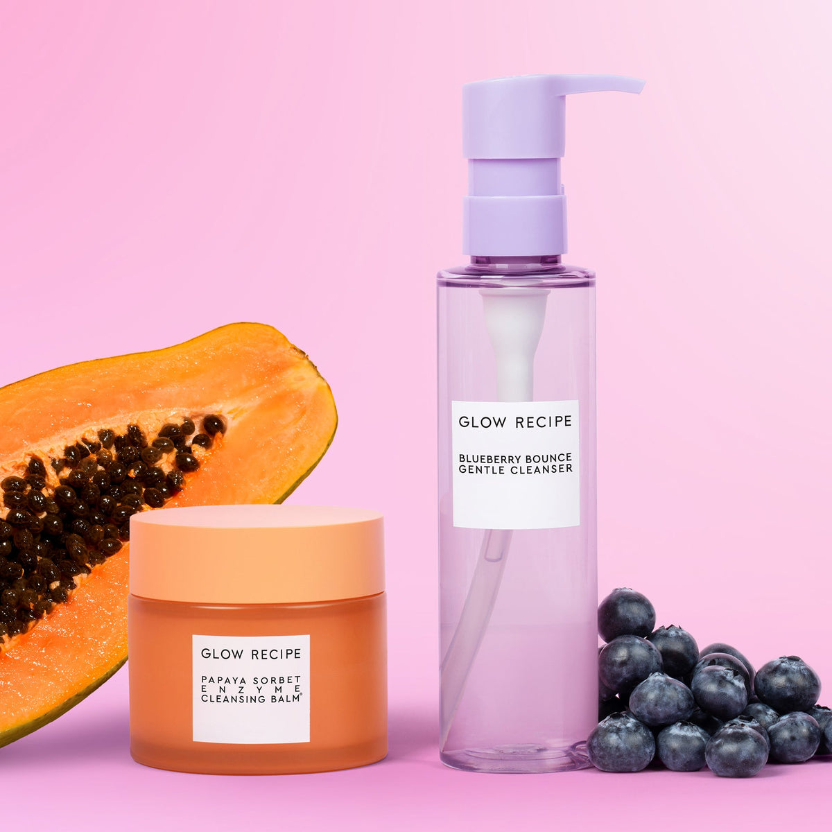 Glow Recipe skincare products including a jar, bottle, and papaya on a pink background