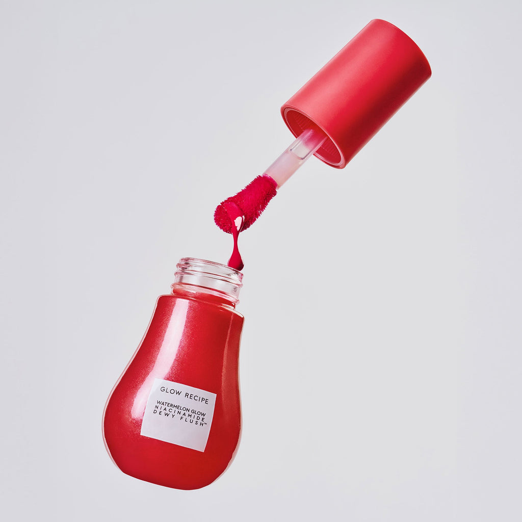 Cherry Flush Dewy Flush serum bottle stands upright, its translucent soft red tint visible through the clear glass.