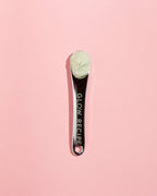 Glow Recipe silver skin care spatula with cream product in scoop on pink background.