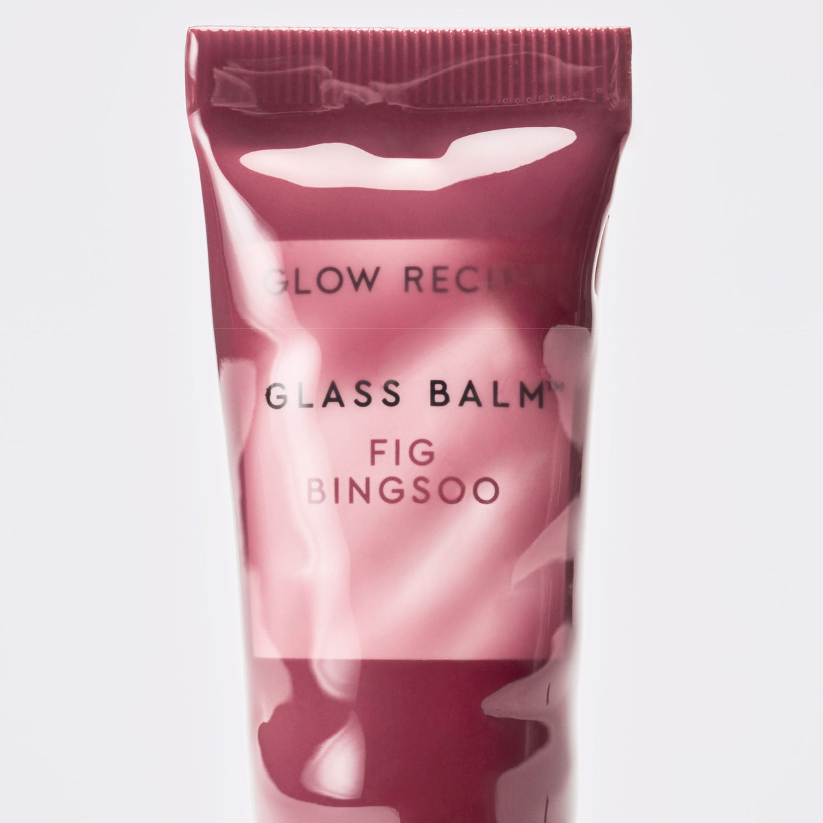 Stylized flat-lay of the Glass Balm tube in Fig Bingsoo arranged with dessert-inspired props.